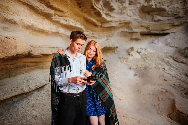 Güzel kadın ve yakışıklı bir battaniyeye sarılmış. Onlar gülümseyen ve bir tablet ekranında bir kum ocağı arka plan üzerinde seyir.