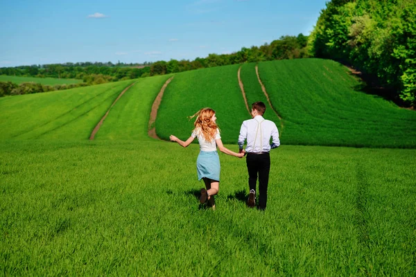 Mutlu aşıklar çayır yeşil çim ve arkasından mavi gökyüzü ile çalışan.