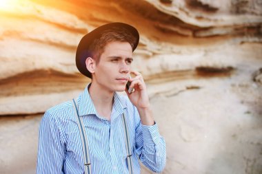 Çekici bir adam bir kum ocağı ortasında duran ve bir akıllı telefon üzerinden arama yapma.