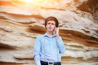 Çekici bir adam bir kum ocağı ortasında duran ve bir akıllı telefon üzerinden arama yapma.