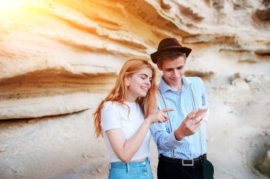 Çekici bir adam ve güzel kadın bir akıllı telefon ekranında bir kum ocağı arka plan üzerinde arıyoruz.