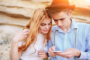 Çekici bir adam ve güzel kadın bir akıllı telefon ekranında bir kum ocağı arka plan üzerinde arıyoruz.