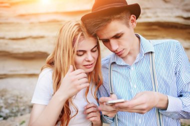 Çekici bir adam ve güzel kadın bir akıllı telefon ekranında bir kum ocağı arka plan üzerinde arıyoruz.