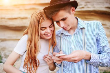 Çekici bir adam ve güzel kadın bir akıllı telefon ekranında bir kum ocağı arka plan üzerinde arıyoruz.