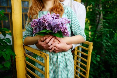 adam bir buket leylak tutan kız arkadaşı sarılma.