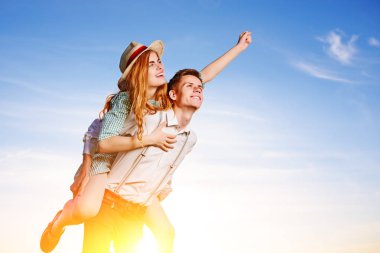 Mutlu kız arkadaşıyla yükseltilmiş el piggybacking genç adam. Neşeli severler rüya.
