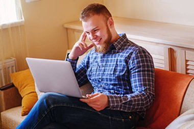 dizüstü bilgisayarınızda evde absorbe çalışan genç adam.