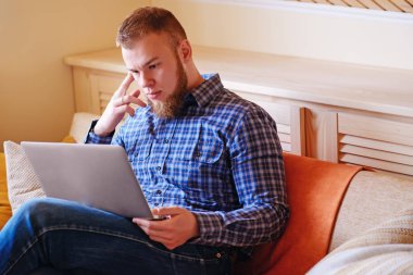 dizüstü bilgisayarınızda evde absorbe çalışan genç adam.