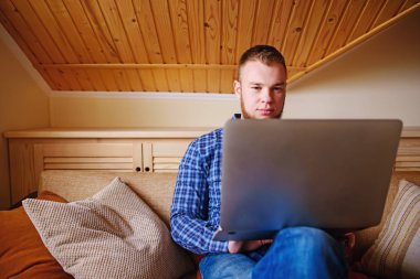 dizüstü bilgisayarınızda evde absorbe çalışan genç adam.