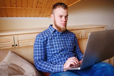 dizüstü bilgisayarınızda evde absorbe çalışan genç adam.