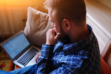 Genç adam sahilde bilgisayarla çalışma. Yakışıklı adam kanepede plajda döşeme dizüstü bilgisayar ile çalışma.