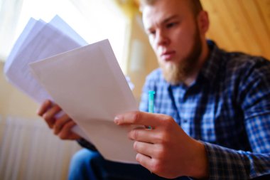 Genç yakışıklı adam kanepede oturan ve bir çalışma kağıdı saatler.