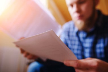 Genç yakışıklı adam kanepede oturan ve bir çalışma kağıdı saatler.