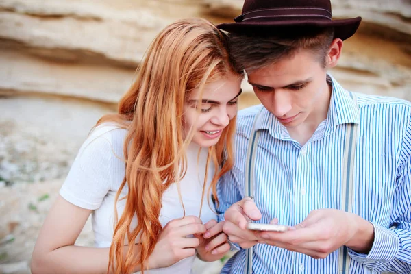 Çekici bir adam ve güzel kadın bir akıllı telefon ekranında bir kum ocağı arka plan üzerinde arıyoruz.