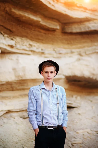 Şık çekici adam bir kum ocağı ortasında duruyor ve kameraya poz veriyor.