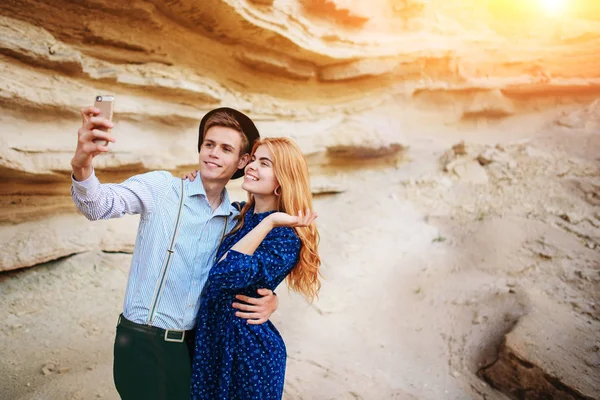 Çekici bir adam güzel bir kadın ile sarılma ve gülümseyerek. Onlar kum ocağı arka plan üzerinde selfie yapıyoruz.