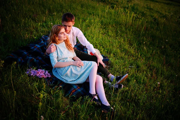 Genç çift ekose parkta oturan ve gün batımında bak.