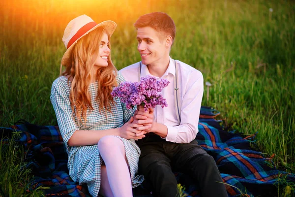 Genç çift, park ve günbatımı bakmak ekose oturan adam kız arkadaşı leylak bir buket verir.