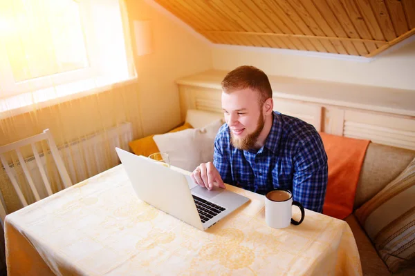 Onun laptop içinde internette sörf rahat genç profesyonel bir yemek odası.