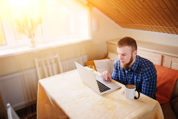 Onun laptop içinde internette sörf rahat genç profesyonel bir yemek odası.