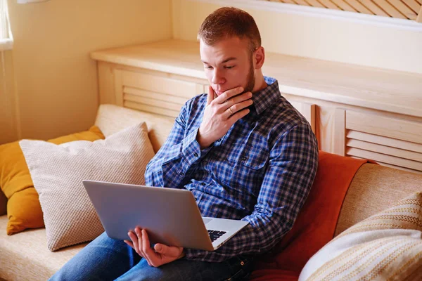 dizüstü bilgisayarınızda evde absorbe çalışan genç adam.