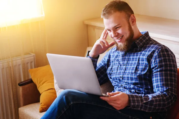 dizüstü bilgisayarınızda evde absorbe çalışan genç adam.