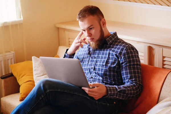 dizüstü bilgisayarınızda evde absorbe çalışan genç adam.