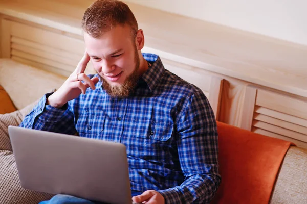 dizüstü bilgisayarınızda evde absorbe çalışan genç adam.