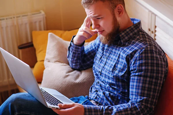 dizüstü bilgisayarınızda evde absorbe çalışan genç adam.