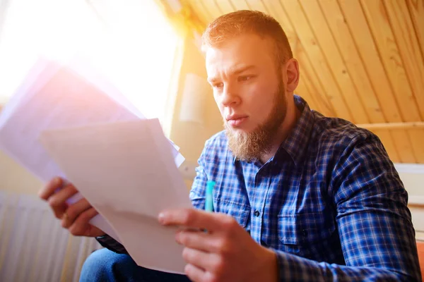 Genç yakışıklı adam kanepede oturan ve bir çalışma kağıdı saatler.
