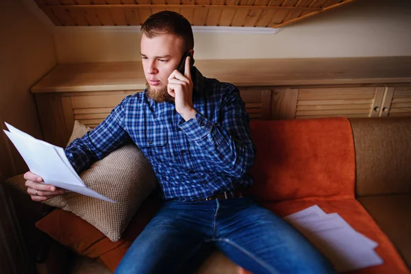 Kağıt basılı tutup evde kanepede otururken cep telefonda konuşurken ciddi olgun adam