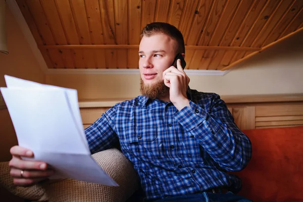 Kağıt basılı tutup evde kanepede otururken cep telefonda konuşurken ciddi olgun adam