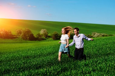 mutlu aşıklar çayır çimen yeşil ve mavi gökyüzü ile çalışan.