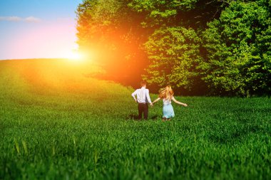 Mutlu aşıklar çayır yeşil çim ve arkasından mavi gökyüzü ile çalışan.