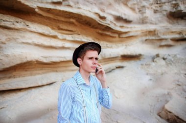 Çekici bir adam bir kum ocağı ortasında duran ve bir akıllı telefon üzerinden arama yapma.