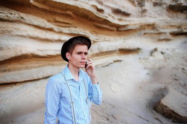 Çekici bir adam bir kum ocağı ortasında duran ve bir akıllı telefon üzerinden arama yapma.