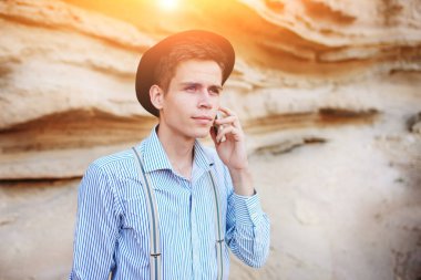 Çekici bir adam bir kum ocağı ortasında duran ve bir akıllı telefon üzerinden arama yapma.