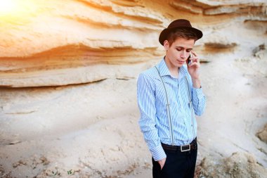 Çekici bir adam bir kum ocağı ortasında duran ve bir akıllı telefon üzerinden arama yapma.