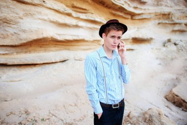 Çekici bir adam bir kum ocağı ortasında duran ve bir akıllı telefon üzerinden arama yapma.