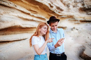 Çekici bir adam ve güzel kadın bir akıllı telefon ekranında bir kum ocağı arka plan üzerinde arıyoruz.