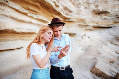 Çekici bir adam ve güzel kadın bir akıllı telefon ekranında bir kum ocağı arka plan üzerinde arıyoruz.
