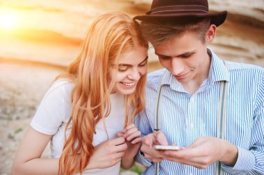 Çekici bir adam ve güzel kadın bir akıllı telefon ekranında bir kum ocağı arka plan üzerinde arıyoruz.