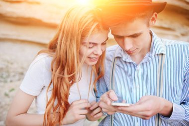 Çekici bir adam ve güzel kadın bir akıllı telefon ekranında bir kum ocağı arka plan üzerinde arıyoruz.