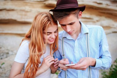 Çekici bir adam ve güzel kadın bir akıllı telefon ekranında bir kum ocağı arka plan üzerinde arıyoruz.