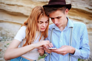 Çekici bir adam ve güzel kadın bir akıllı telefon ekranında bir kum ocağı arka plan üzerinde arıyoruz.