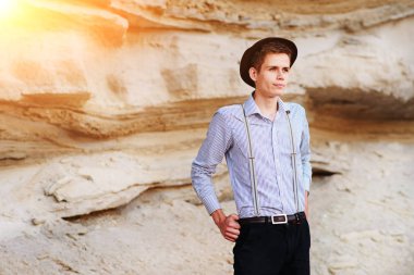 Şık çekici adam bir kum ocağı ortasında duruyor ve kameraya poz veriyor.