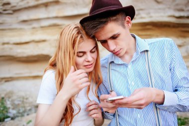 Çekici bir adam ve güzel kadın bir akıllı telefon ekranında bir kum ocağı arka plan üzerinde arıyoruz.