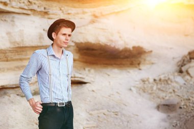 Şık çekici adam bir kum ocağı ortasında duruyor ve kameraya poz veriyor.