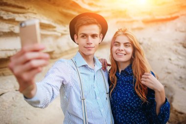 Çekici bir adam güzel bir kadın ile sarılma ve gülümseyerek. Onlar kum ocağı arka plan üzerinde selfie yapıyoruz.