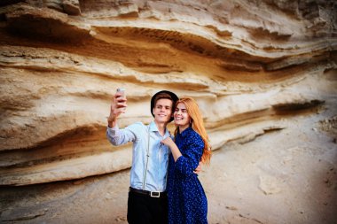 Çekici bir adam güzel bir kadın ile sarılma ve gülümseyerek. Onlar kum ocağı arka plan üzerinde selfie yapıyoruz.